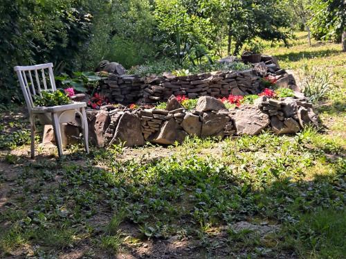 a garden with a chair and a rock wall at Hotel Окремий Будинок-Апартаменти in Rakoshyno