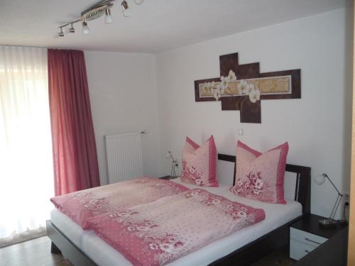 a bedroom with a pink bed with a cross on the wall at Ferienwohnung Aletsee in Pfronten