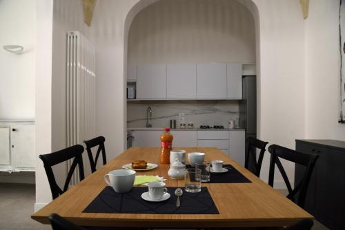 a kitchen with a wooden table with cups and dishes on it at Li Frati Suite in Lecce