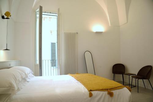 a white bedroom with a bed and two chairs at Li Frati Suite in Lecce