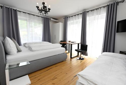 a bedroom with two beds and a table and window at Enjoyit Rooms in Velden am Wörthersee