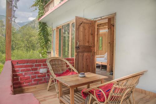 a patio with a table and chairs and a door at Sharda Resort-Tirthan Valley in Banjār