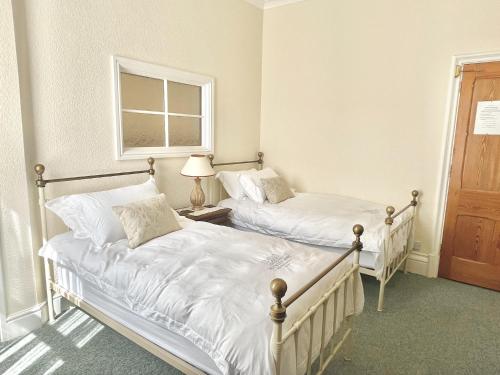 two twin beds in a bedroom with a window at The Buckley Arms in Dinas Mawddwy