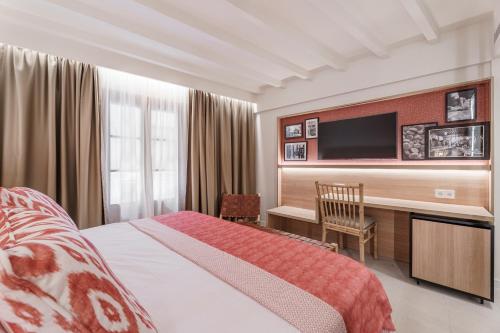 a bedroom with a bed and a desk with a television at Can Guixe - Turismo de Interior in Inca