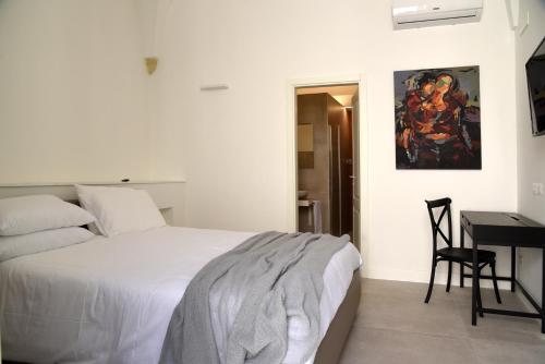 a white bedroom with a bed and a desk at Li Frati Suite in Lecce