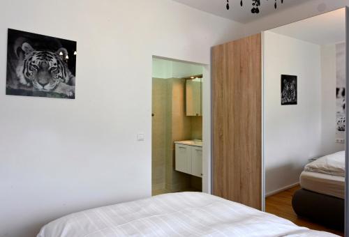 a white bedroom with a bed and a bathroom at Enjoyit Rooms in Velden am Wörthersee