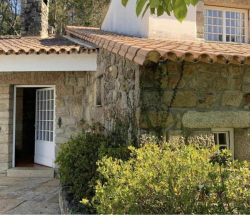 una casa in pietra con una porta bianca e alcuni cespugli di Lovely 6-Bed Cottage in Barcelos - Vila Cova a Barcelos