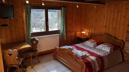 1 dormitorio con cama, escritorio y ventana en La source, en Sondernach