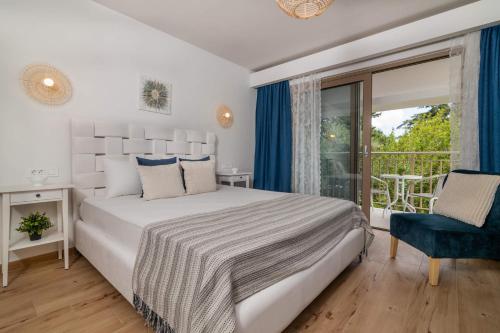 a white bedroom with a bed and a balcony at Villa Ionio Deste by Villa Plus in Vasilikos