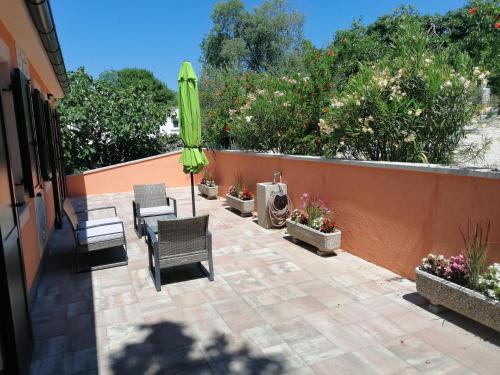 a patio with an umbrella and chairs and plants at The Forest House Krk 2 in Kras