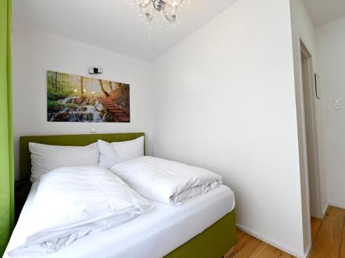 a bedroom with a bed with white sheets and a chandelier at Enjoyit Rooms in Velden am Wörthersee