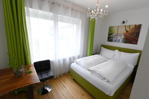 a bedroom with a bed and a desk and a window at Enjoyit Rooms in Velden am Wörthersee