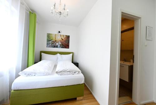 a bedroom with a green and white bed with a chandelier at Enjoyit Rooms in Velden am Wörthersee