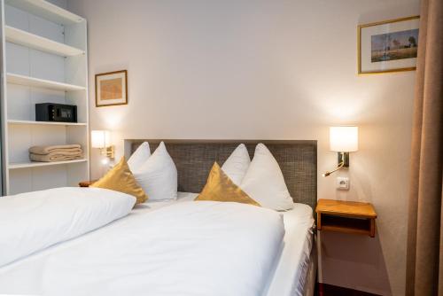 a bedroom with two beds with white sheets and yellow pillows at Cityhotel Trumer Stube in Salzburg