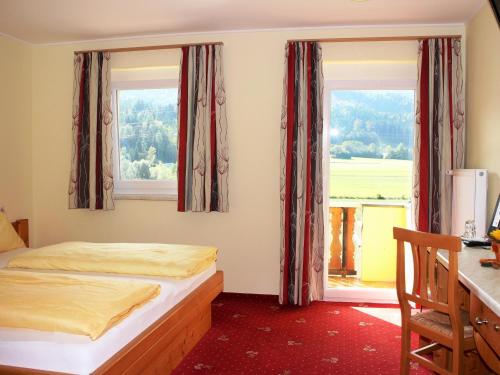 a bedroom with two beds and a desk and two windows at Gasthof Pension Post "Zenz" in Latschach ober dem Faakersee