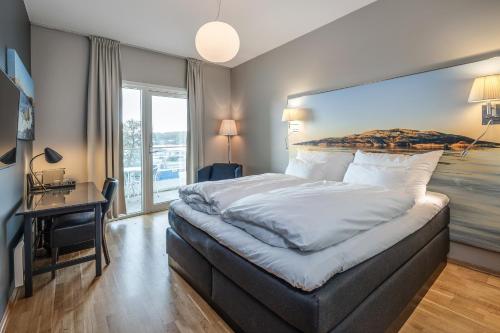 a bedroom with a large bed and a desk at Quality Hotel Grand Larvik in Larvik