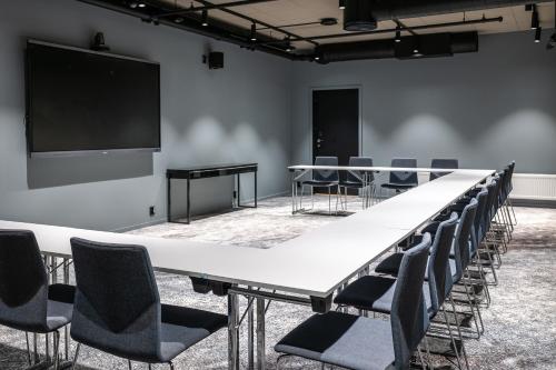 a conference room with tables and chairs and a screen at Quality Hotel Grand Larvik in Larvik