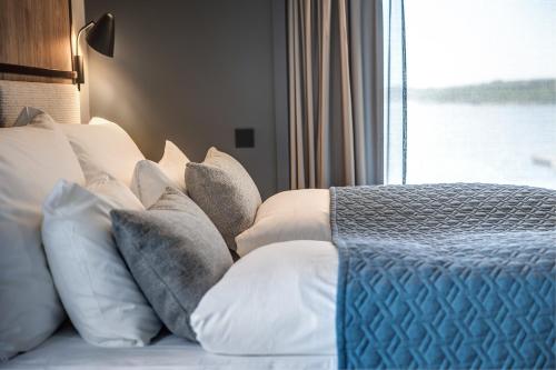 a bedroom with a bed with white pillows and a window at Quality Hotel Grand Larvik in Larvik
