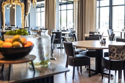 a dining room with tables and chairs and a bowl of fruit at Quality Hotel Grand Larvik in Larvik