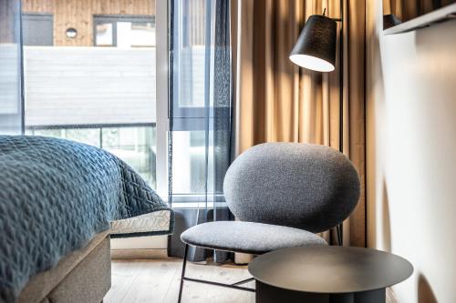 a bedroom with a chair and a bed and a lamp at Quality Hotel Grand Larvik in Larvik