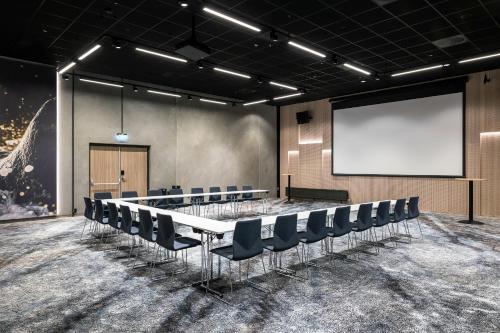 a conference room with a table and chairs and a screen at Quality Hotel Grand Larvik in Larvik