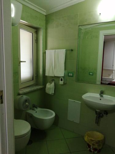 a green bathroom with a toilet and a sink at Hotel Tiffany in Varcaturo