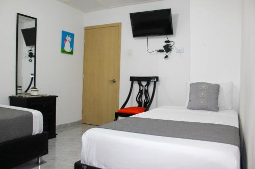 a bedroom with two beds and a television on the wall at Hotel Poblado Suite in Barranquilla