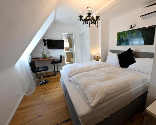 a bedroom with a white bed and a chandelier at Enjoyit Rooms in Velden am Wörthersee