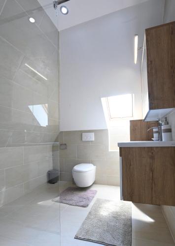 a bathroom with a toilet and a glass shower at Enjoyit Rooms in Velden am Wörthersee
