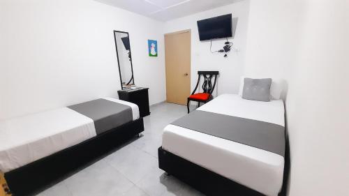 a bedroom with two beds and a tv in it at Hotel Poblado Suite in Barranquilla