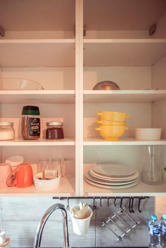 a kitchen cabinet filled with dishes and a sink at Zimna Apartments in Kwidzyn