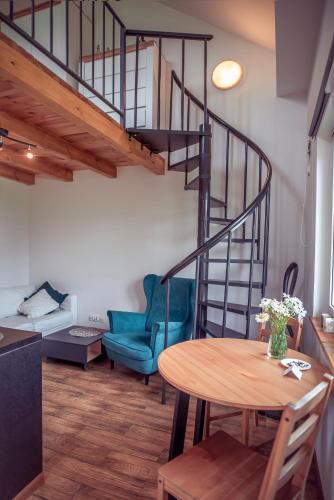 a living room with a table and a spiral staircase at Zimna Apartments in Kwidzyn