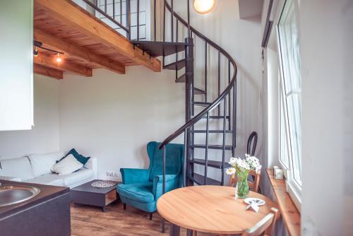 a living room with a spiral staircase and a table at Zimna Apartments in Kwidzyn