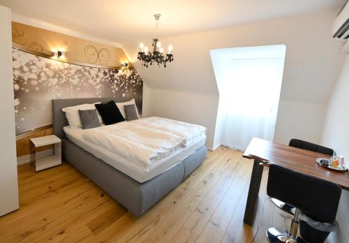a bedroom with a bed with a chandelier and a table at Enjoyit Rooms in Velden am Wörthersee