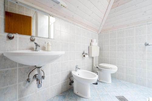 a white bathroom with a sink and a toilet at Hostel Kronotop in Triglav National Park in Log pod Mangartom