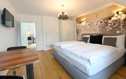 a bedroom with a large white bed and a wooden table at Enjoyit Rooms in Velden am Wörthersee