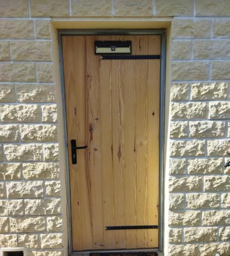 une porte en bois sur un mur de briques dans l'établissement La chambre secrète, à Longueval