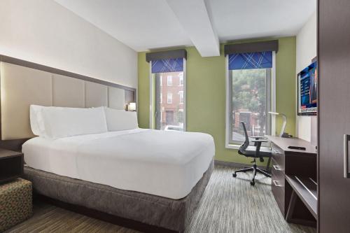 a large white bed in a room with a desk and window at Hotel 1200 in Brooklyn