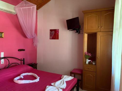 a bedroom with pink walls and a bed with a pink bedspread at Palma Sidari Corfu in Sidari