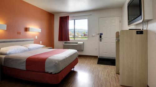 a hotel room with a bed and a flat screen tv at Super 8 by Wyndham Woods Cross - Salt Lake City North in Woods Cross
