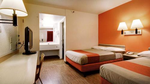 a hotel room with two beds and a television at Super 8 by Wyndham Woods Cross - Salt Lake City North in Woods Cross