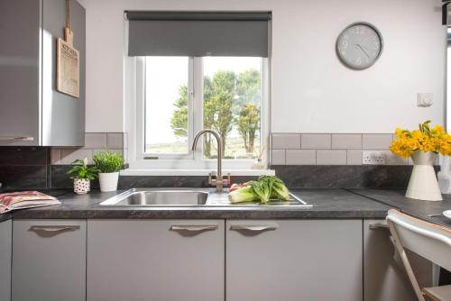 a kitchen with a sink and a window at Wheal Prosper- Beautifully Fitted Wooden Lodge Helston Cornwall in Helston