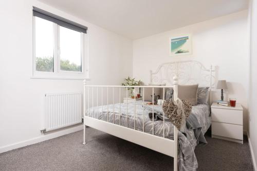 Un dormitorio blanco con una cama blanca y una ventana en Wheal Prosper- Beautifully Fitted Wooden Lodge Helston Cornwall en Helston