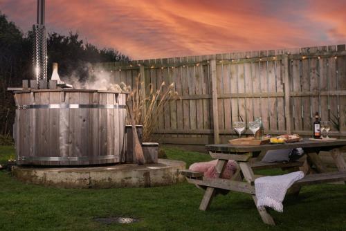 a grill and picnic table with a barrel and wine glasses at Wheal Prosper- Beautifully Fitted Wooden Lodge Helston Cornwall in Helston