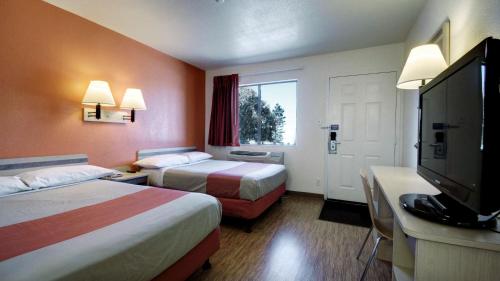 a hotel room with two beds and a flat screen tv at Super 8 by Wyndham Woods Cross - Salt Lake City North in Woods Cross