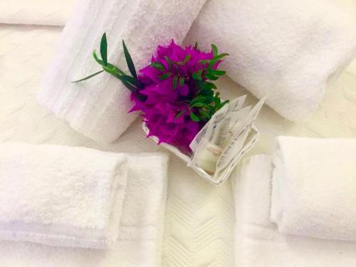 a pink flower sitting on a bed with towels at Villa Franci in Santa Teresa Gallura