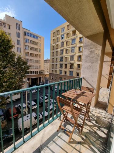 uma mesa e cadeira numa varanda com edifícios em La Caisserie Vieux-port / une chambre et balcon em Marselha