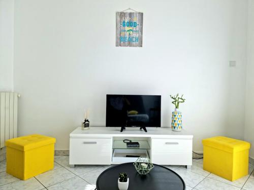 un soggiorno con TV e 2 sgabelli gialli di La Caisserie Vieux-port / une chambre et balcon a Marsiglia