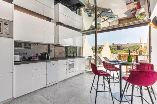 une cuisine avec des placards blancs et une table avec des chaises roses dans l'établissement After Eight Heliopolis Naturiste, au Cap d'Agde