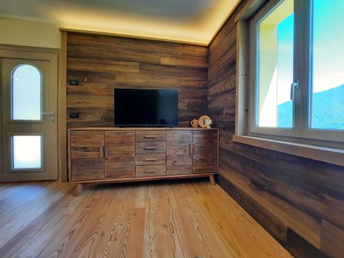 a living room with a tv on a wooden wall at CasAmici in Bognanco